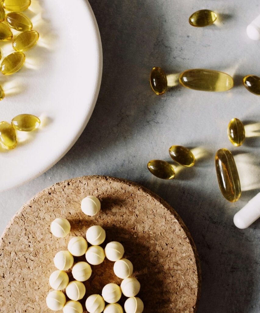 Close-up of table top with variety of loose neutral-colored tablets and capsules